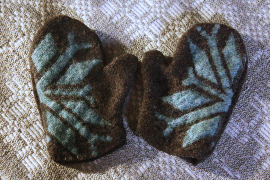 A photo of a child's brown mittens with a light blue snowflake pattern made from wool recycled from a sweater